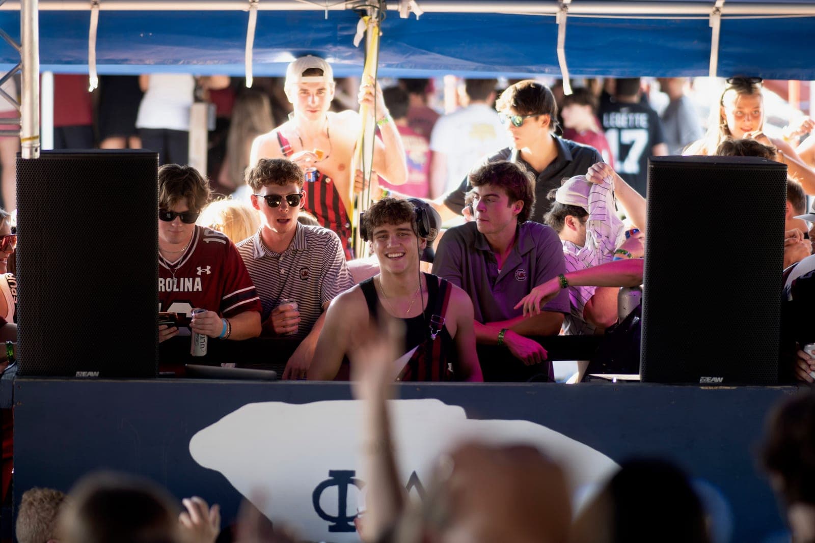 Daytime tailgate DJ set, packed crowd under a tent